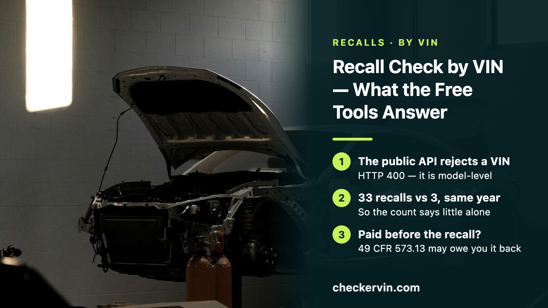 A partly dismantled car raised in a workshop, beside a panel about checking recalls by VIN.